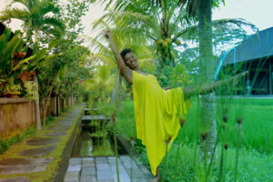 Anastasia White modeling in a yellow dress surrounded by palm trees