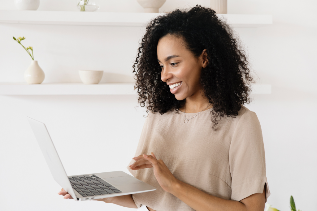 woman smiling and holding laptop in her hands