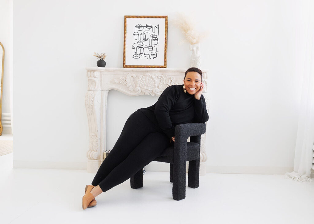 Shanté smiling and leaning on a chair