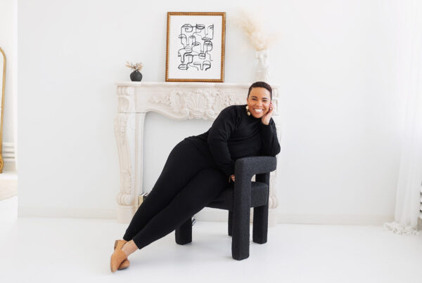 Shanté smiling and leaning on a chair